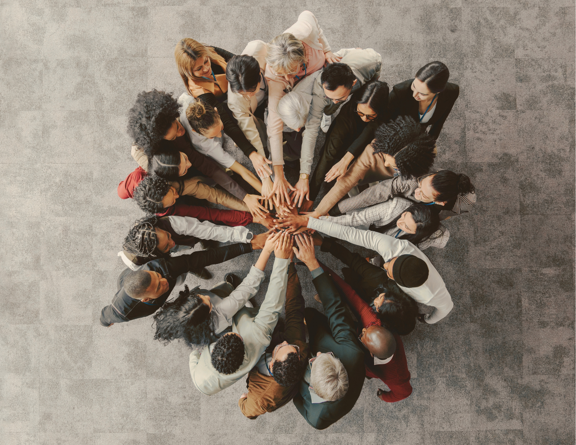 People standing in a circle with their hands extended to the center of the group